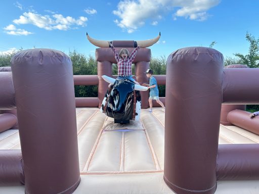 Ein Mensch reitet auf einem mechanischen Bullen in einer aufblasbaren Arena.