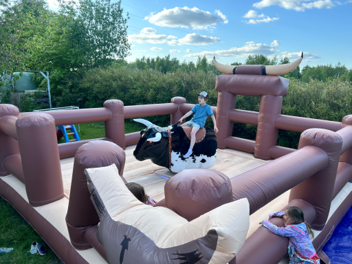 Ein Kind reitet auf einem aufblasbaren Bullen in einem luftigen Garten.